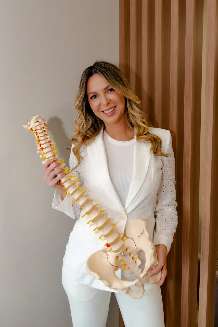 Dra. Maria Alice Guina segurando modelo anatômico da coluna